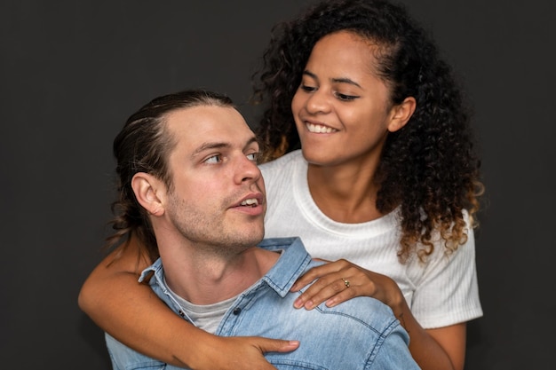 Romantique jeune couple heureux homme caucasien et femme afro-américaine sourient et s'amusent ensemble le jour de la Saint-Valentin sur fond noir