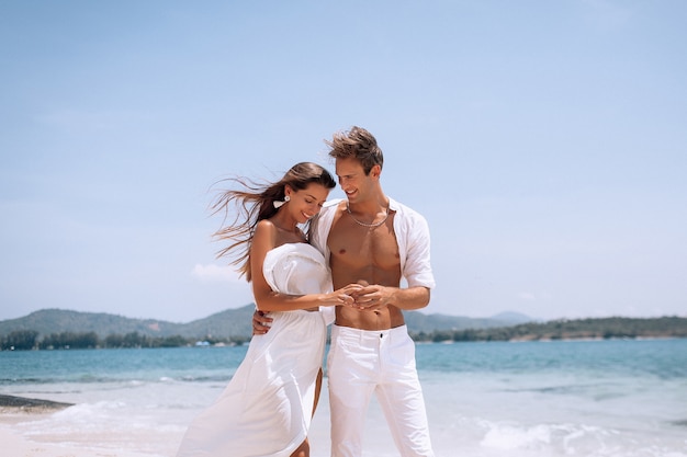 Romantique jeune couple en vêtements blancs, profitant des vacances d'été sur la plage