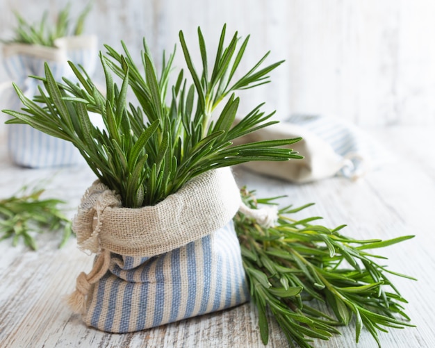 Romarin frais dans une pochette décorative sur une vieille table en bois