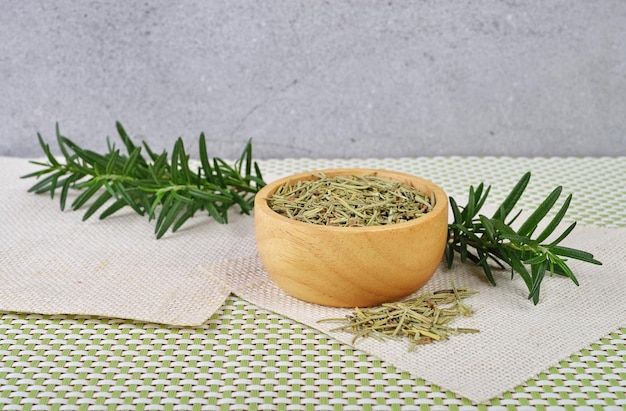 Romarin séché dans une tasse en bois et branches de romarin frais