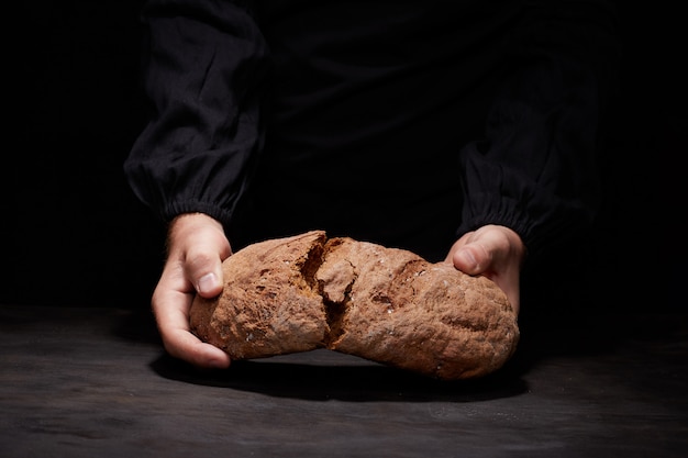 rompez le pain avec moi. Portrait de chef masculin rompant le pain au levain fraîchement cuit