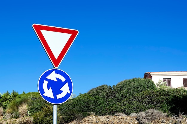 Rond-point et panneaux publicitaires entourés de végétation sous un ciel bleu