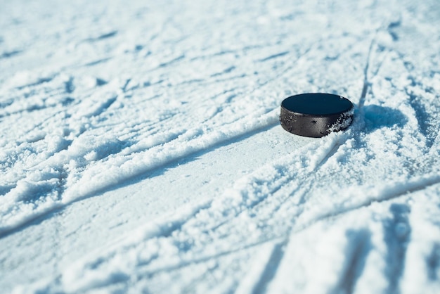 La rondelle de hockey noir se trouve sur la glace au stade