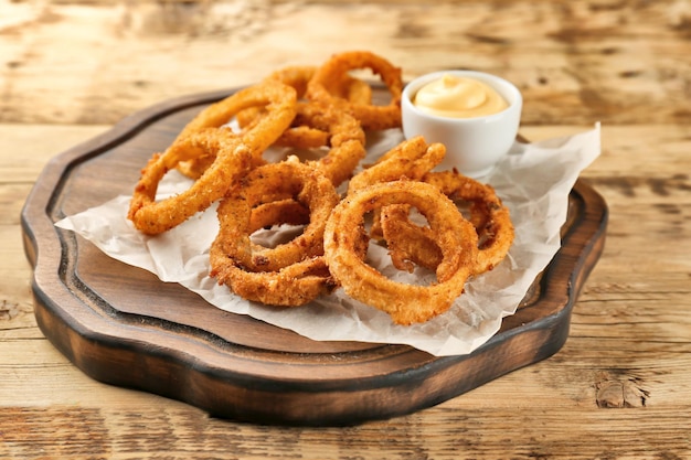 Rondelles d'oignon frites avec sauce sur planche de bois