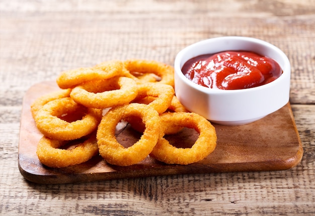 Rondelles d'oignon avec ketchup sur planche de bois