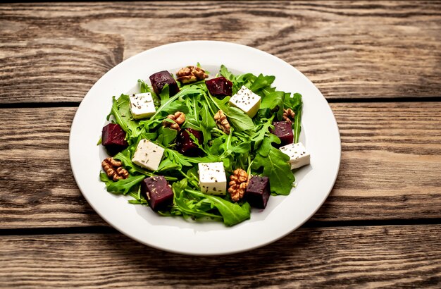 Roquette, fromage, betterave, salade de noix sur un fond de bois