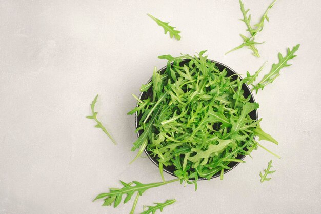 Roquette verte fraîche dans un bol en céramique sur la vue de dessus de table de cuisine grise espace de copie Herbe épicée de printemps pour une alimentation saine