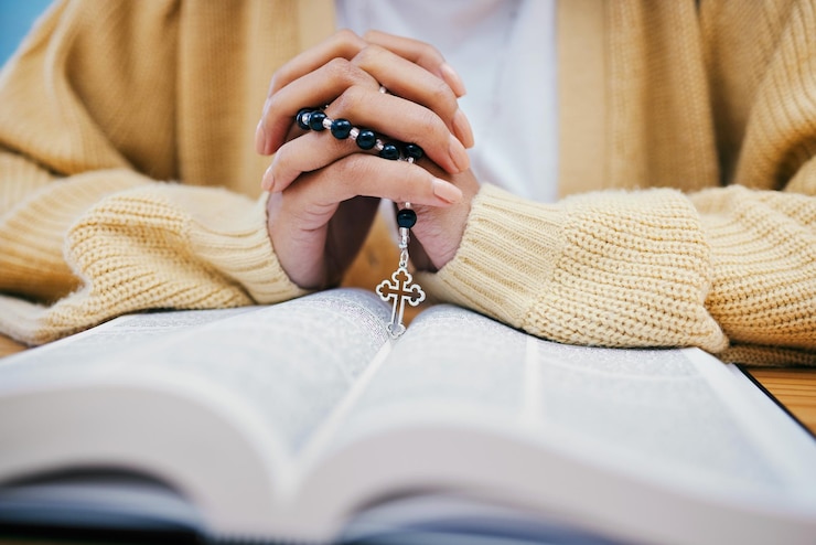 Photo rosaire biblique et mains de femme en prière étudiant la religion au bureau à la maison avec la foi chrétienne et la connaissance de dieu lire l'espérance et la fille à la table avec le livre saint pour la louange de l'évangile et des perles