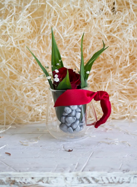 Rose dans une coupe en verre avec un arc rouge