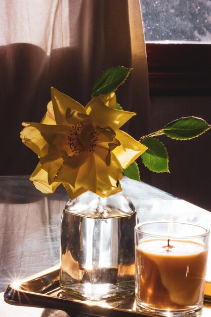 Photo une rose jaune est dans un vase à côté d'une bougie et d'une bougie.