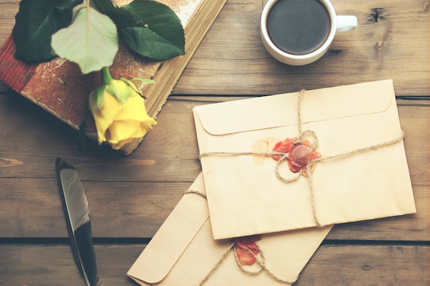 Rose jaune avec des lettres, un livre et un café sur la table