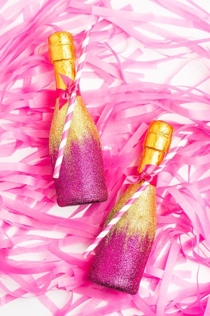 Photo rose et or mini bouteilles de champagne avec des confettis dorés et des guirlandes à plat
