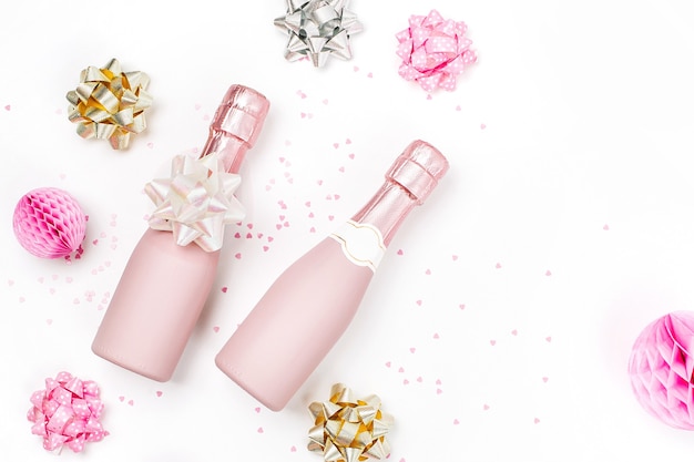 Rose pâle Mini bouteilles de champagne avec confettis et guirlandes. Mise à plat. Nouvel an/Célébration de Noël ou thème du concept de mariage. Mise à plat, vue de dessus