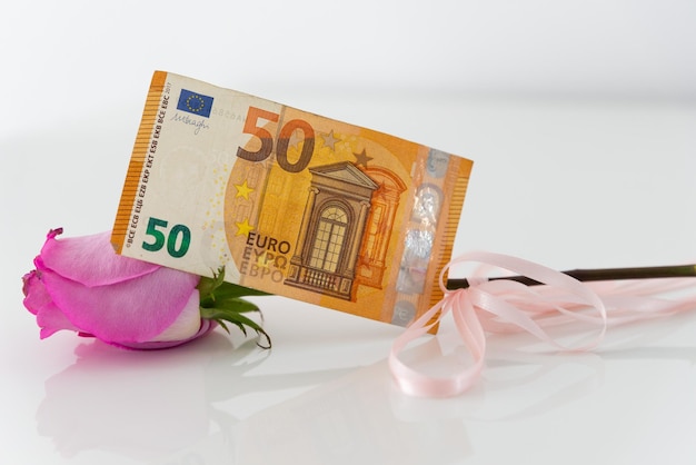 Une rose rose en cadeau avec un billet en euros