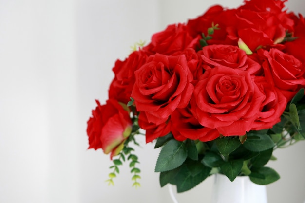 Rose rouge dans un vase blanc sur blanc