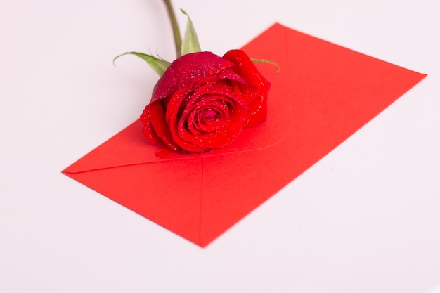 Rose rouge et enveloppe avec espace copie, pose sur lit blanc.