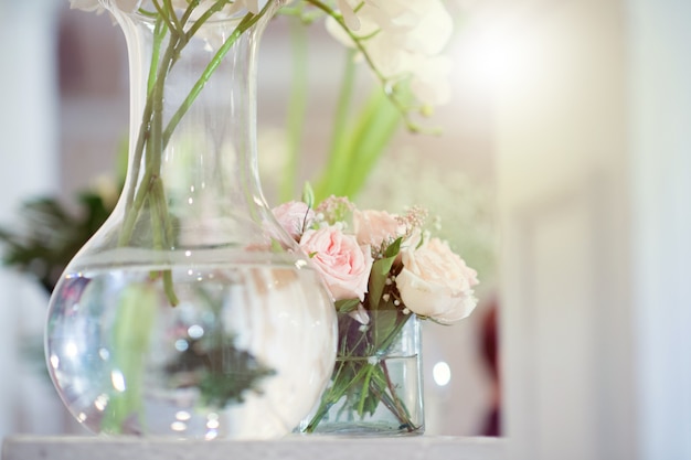 Roses blanches dans des vases en verre clair