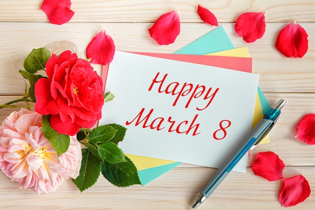 Des roses et une carte avec l'inscription - Happy March 8. Journée internationale de la femme