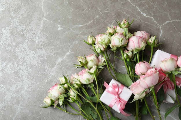 Roses et coffrets cadeaux sur fond texturé gris