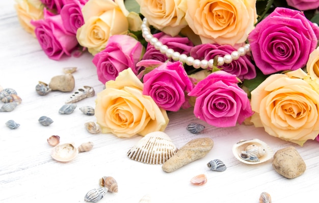 Photo roses, coquillages et perles sur un dos en bois