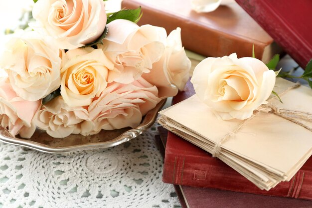 Roses fraîches avec vieux livre et lettres sur fond de table en bois de couleur. Notion de cru