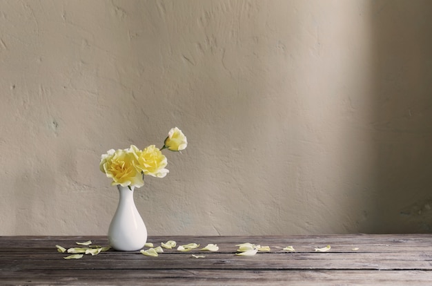 Roses jaunes dans un vase blanc sur le mur de fond