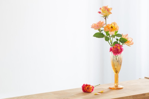 Roses oranges et roses dans un vase en verre à l'intérieur blanc