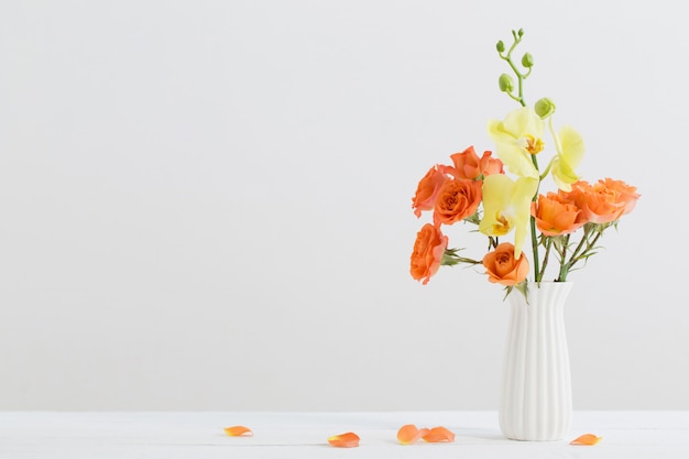 Roses et orchidées dans un vase blanc