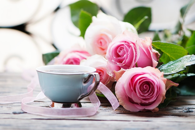 Roses roses et café sur la table en bois