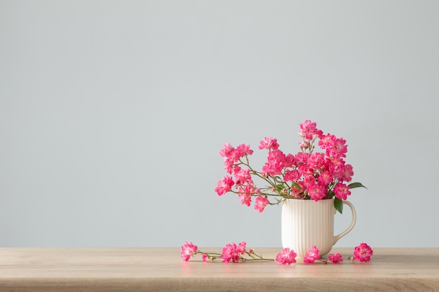 Roses roses dans un vase en céramique sur une étagère en bois