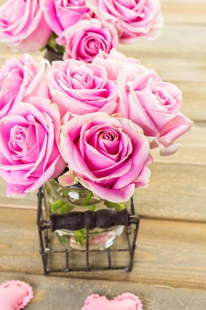 Roses roses en pots sur table en bois rustique.