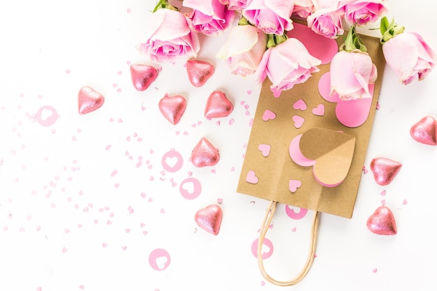 Photo roses roses et sac cadeau artisanal sur fond blanc.