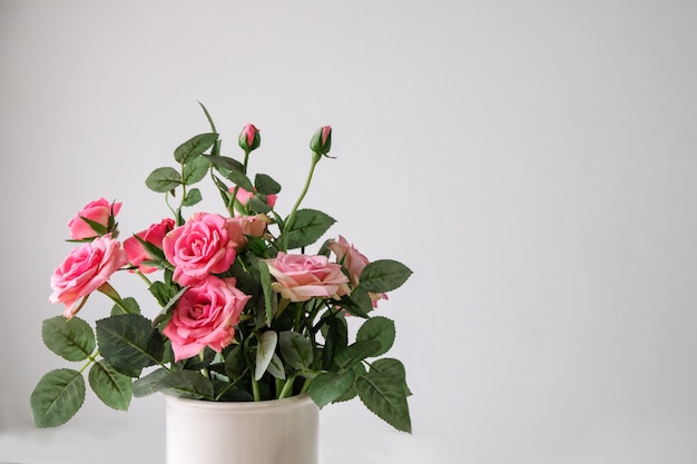 Les roses roses sont dans un vase blanc.