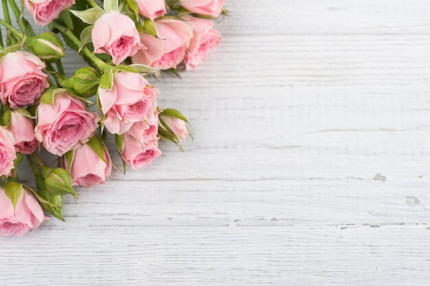 Roses roses sur une surface en bois blanche