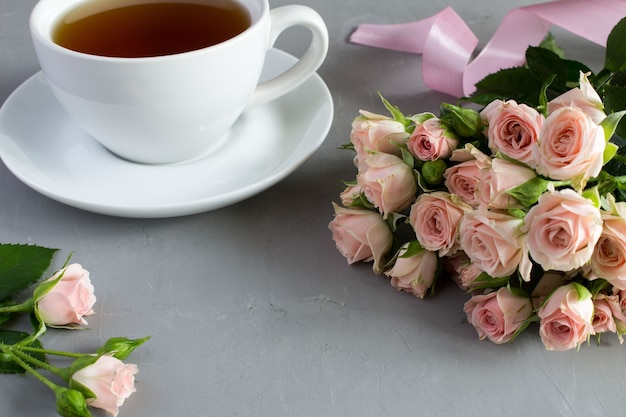 Roses roses et thé sur table se bouchent