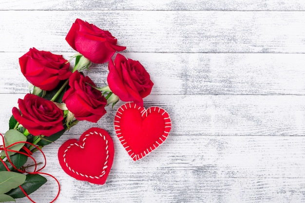 Roses rouges et coeurs fabriqués à la main sur fond blanc en bois. Le concept de la Saint-Valentin. Copiez l'espace pour votre texte