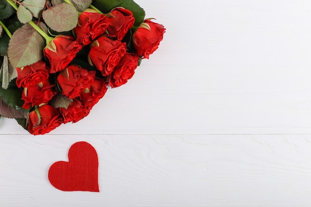 Roses rouges et coeurs sur une table en bois blanche