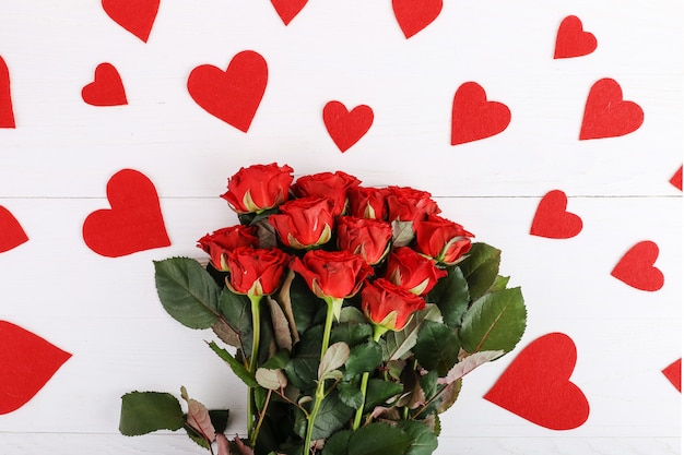 Roses rouges et coeurs sur une table en bois blanche