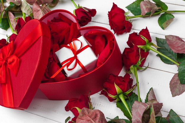 Roses rouges et coffret cadeau sur une table en bois