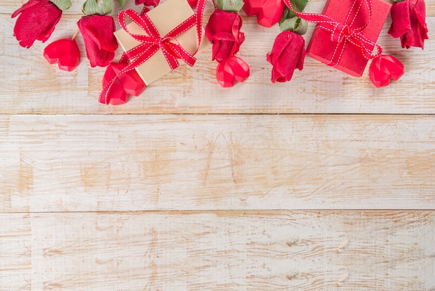 Roses rouges et coffrets cadeaux et décor de coeur sur une table en bois blanche. Vacances de la Saint-Valentin