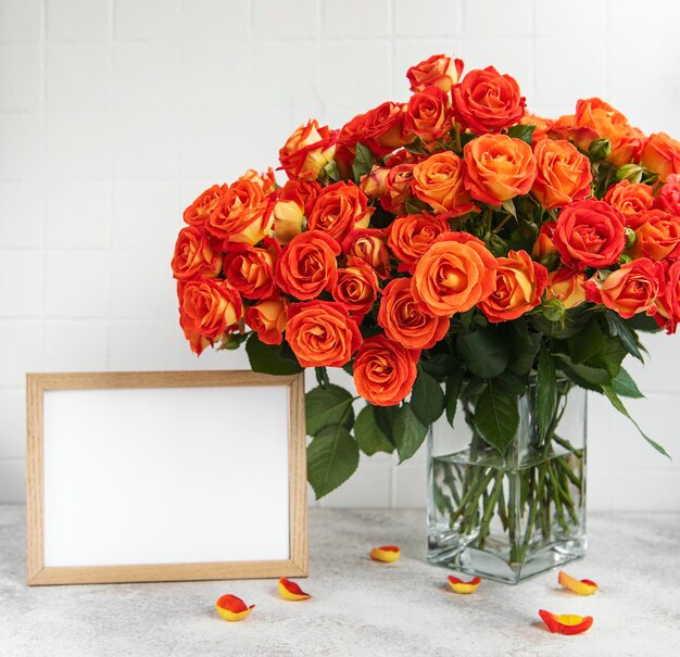 Roses rouges dans un vase en verre avec un cadre photo vide sur la table