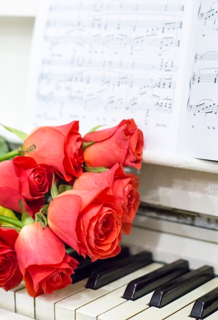 Roses rouges sur un piano blanc avec des notes et des guirlandes