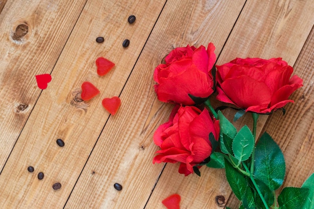 Roses rouges et sucrerie sous forme de coeur sur un fond en bois