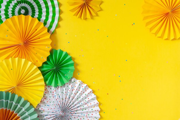 Rosettes en papier multicolores de différentes tailles sur fond jaune.