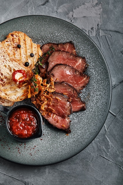 Rôti de bœuf juteux avec ciabatta à la sauce tomate est joliment tranché et disposé sur des assiettes