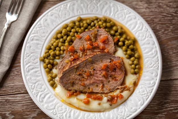 Rôti de boeuf avec purée de pommes de terre et petits pois