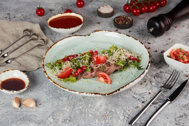 Rôti de boeuf avec roquette, tomates et fromage sur une assiette