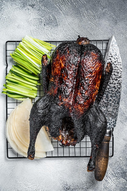 Rôti entier de canard laqué aux herbes sauce riz Pancake Concombre et oignon Fond blanc Vue de dessus