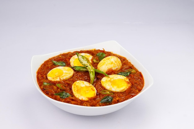 Rôti d'oeuf ou oeuf indien masala curry rôti d'oeuf rouge épicé disposé dans un bol en céramique blanche