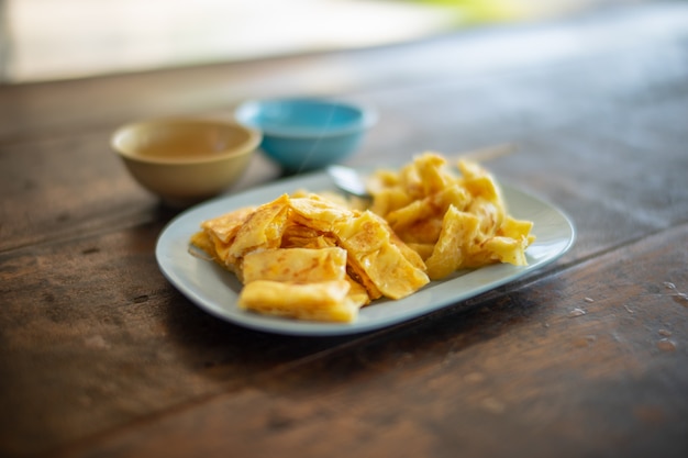 Photo roti d'oeufs jaunes dans un pot en plastique bleu sur une table en bois.